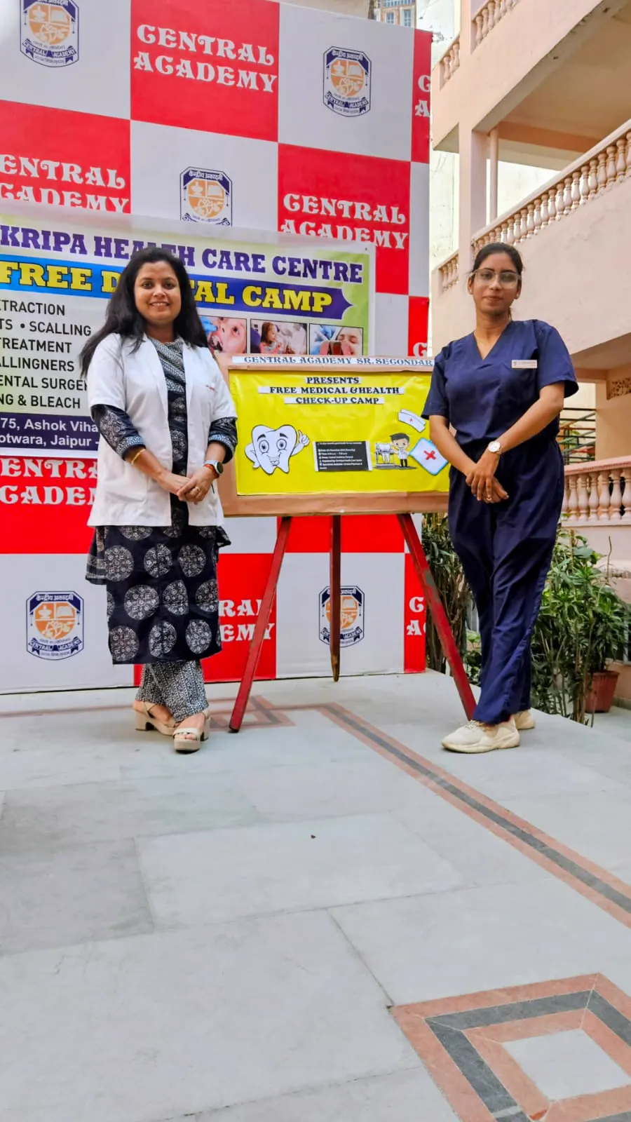 Clinic team members standing beside the free dental camp banner and poster