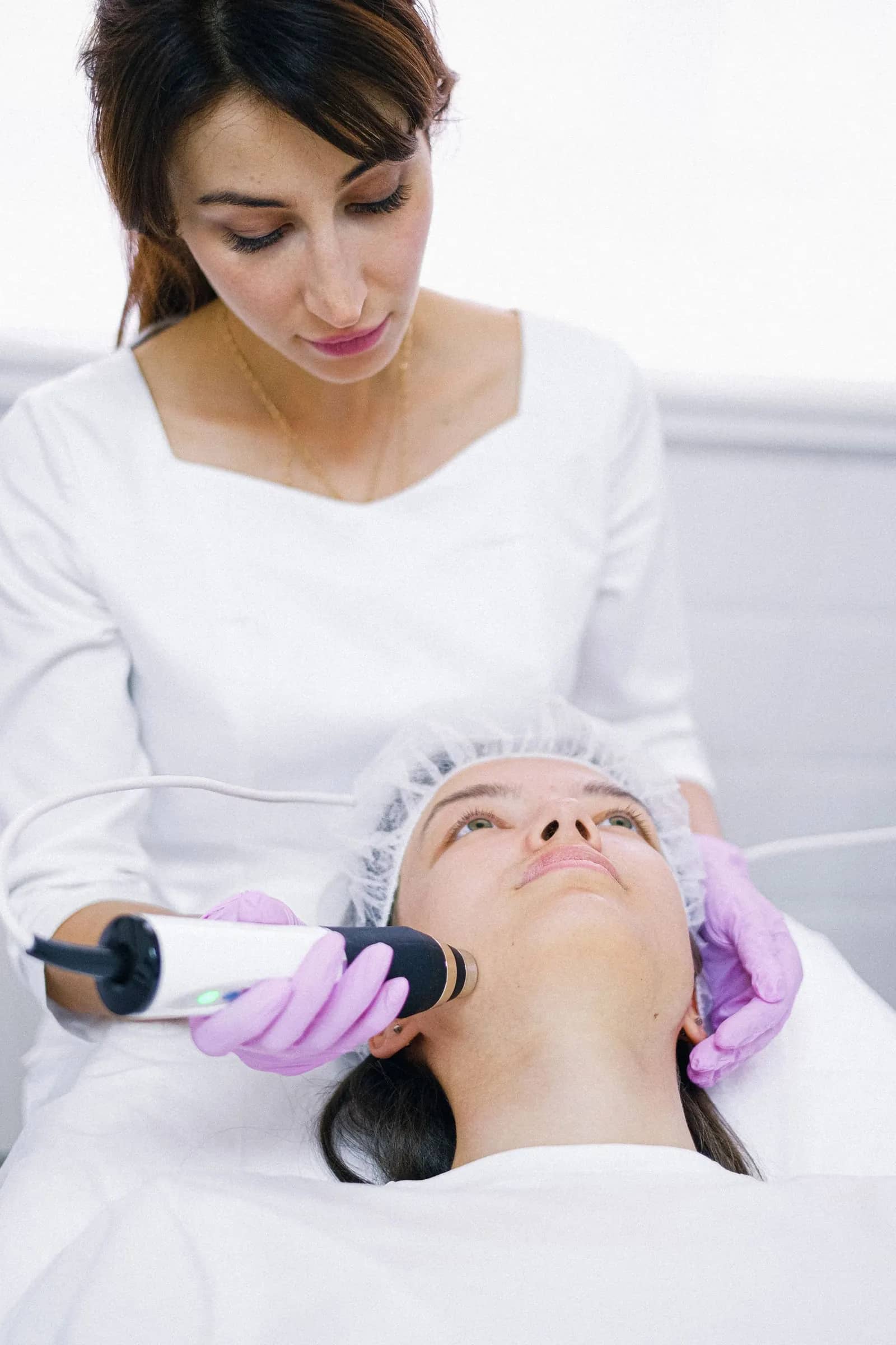 A practitioner performing a facial treatment on a patient lying down